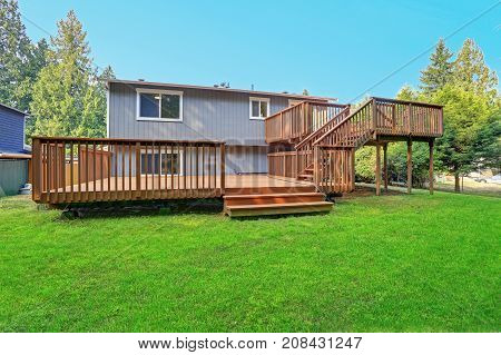 Backyard View Of Grey Rambler House With Upper And Lower Decks