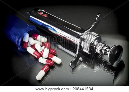 Some red and white capsules  out of a boat together with syringe