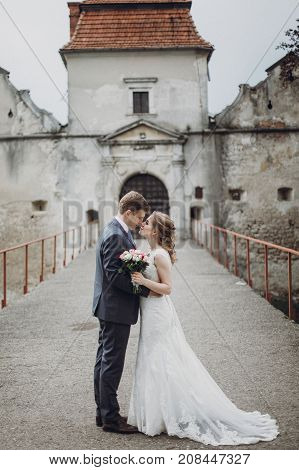 Beautiful Gorgeous Bride And Groom Kissing. Happy Wedding Couple Hugging And Embracing At Old Castle