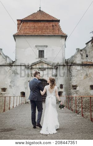 Beautiful Gorgeous Bride And Groom Walking. Happy Wedding Couple Hugging And Embracing At Old Castle