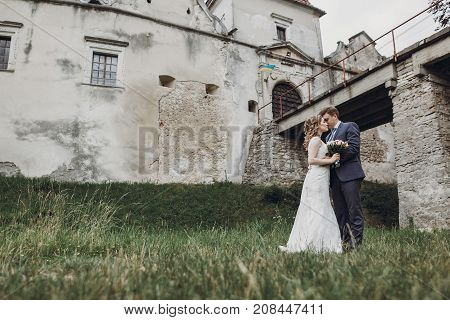 Beautiful Gorgeous Bride And Groom Walking In Sunny Park And Kissing. Happy Wedding Couple Hugging I