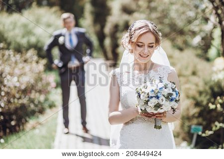 Beautiful Gorgeous Bride And Groom Walking In Sunny Spring Park And Enjoying Day. Happy Wedding Coup