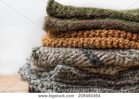 Stack of Handmade Warm Knitted Socks Scarfs Mittens From Rough Wool Yarn Brown Beige Grey on Wood Table. Close up. Winter Autumn Eco Fashion Kinfolk Style. Natural Materials