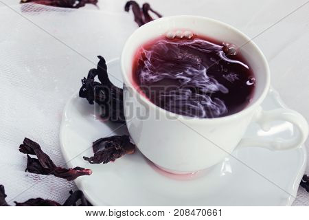 white porcelain mug with tea karkade on white tulle