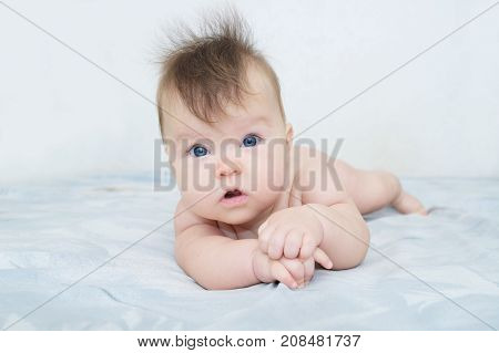 Newborn baby portrait cute and adorable in her three month infant child with blue eyes lying on bed looking at camera