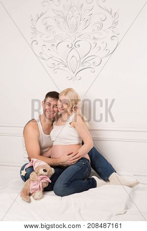 Beautiful pregnant couple in love on the background. Hands of husband on the tummy of his pregnant wife. Young man tenderly stroked pregnant belly of his wife. Husband kissing pregnant belly.