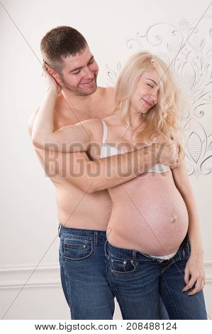 Beautiful pregnant couple in love on the background. Hands of husband on the tummy of his pregnant wife. Young man tenderly stroked pregnant belly of his wife. Husband kissing pregnant belly.