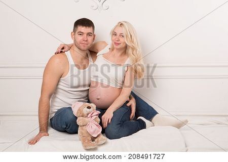 Beautiful pregnant couple in love on the background. Hands of husband on the tummy of his pregnant wife. Young man tenderly stroked pregnant belly of his wife. Husband kissing pregnant belly.