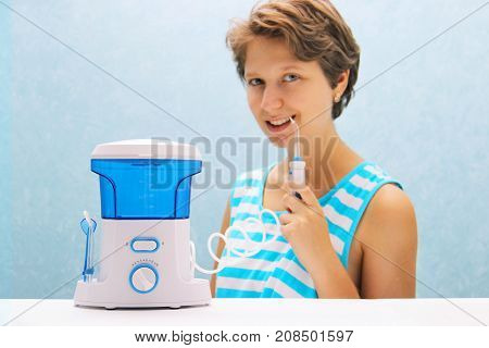 Beautiful Girl Flushes Her Teeth With An Oral Irrigator. The Woman Smiles And Holds The Irrigator Ha