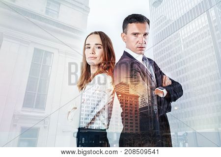 Reliable people. Strict elegant man looking concentrated while standing with his young cheerful colleague