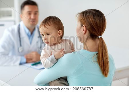 medicine, healthcare, pediatry and people concept - happy woman with baby and doctor at clinic