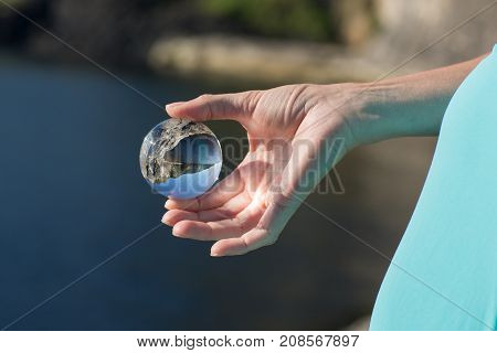Glass ball in hand, outdoor, sunligh focus on skin, landscape