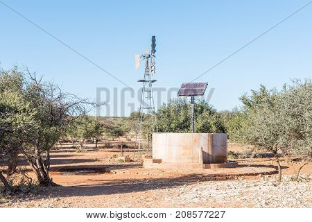 A water-pumping windmill and solar panels for a waterpump near Schmidtsfrift a village in the Northern Cape Province of South Africa