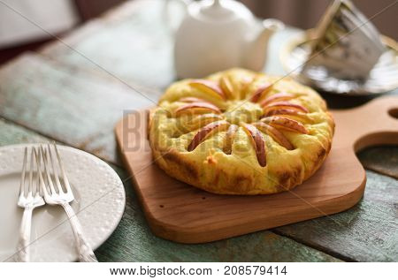 Homemade apple cake with teaware on shabby blue wooden background selective focus