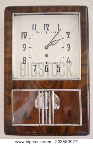 Soviet wall brown simple clock with pendulum is on white wall