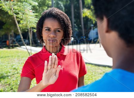 African american woman showing stop sign to man outdoor in city