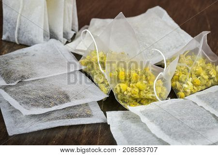 Herbal tea bags stacked on wooden background.