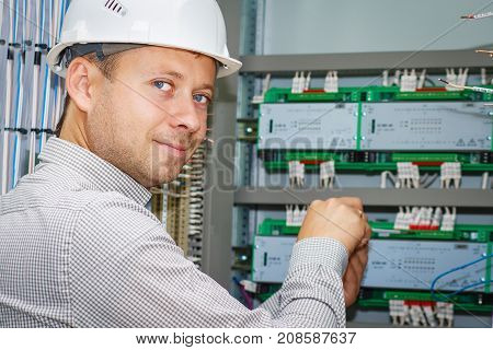 engineer tests industrial electrical circuits in control terminal box. Electrician adjusts electric equipment in automation panel