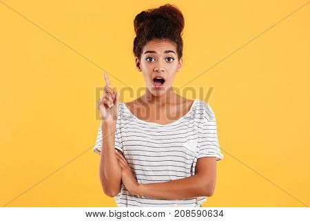 Happy surprised afro-american lady having idea and looking camera with opened mouth iolated over yellow