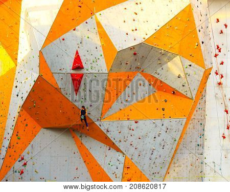 The young woman on rock wall in sport center outdoor