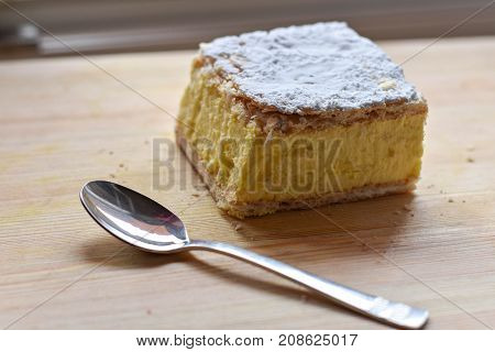 Sweet cream pie slice and silver spoon on a wooden background