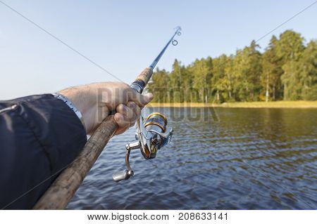 Fishing on a lake. Fishing rod with a reel in hand. Vew of the shore.