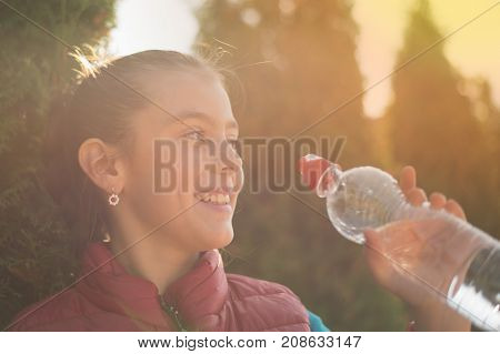 Beautiful girl drinking water after jogging in outdoor. A  beautiful girl is drinking water the hot sun in the park. Healthily concept. Healthy lifestyle concept. copy space. Portrait  beautiful girl