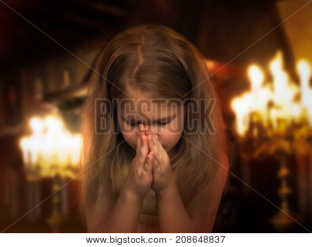 Beautiful little girl folded her hands in a prayerful gesture. Child praying in the temple