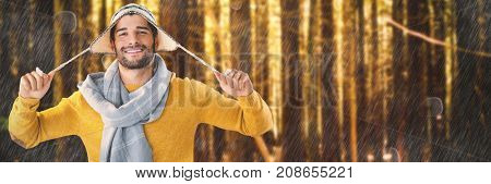 Portrait of smiling man holding wooly hat against trees in a woods