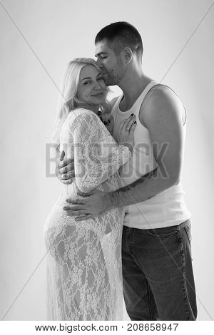 Beautiful pregnant couple in love on the background. Hands of husband on the tummy of his pregnant wife. Young man tenderly stroked pregnant belly of his wife. Husband kissing pregnant belly.