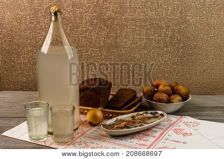 Ukrainian National Drink And Snack. The Big Bottle And Glass Of Moonshine On The Old Wooden Table
