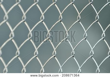 Silvery Fence Made Of Metal Mesh Of The Slab, On A Gray Fuzzy Background. Close-up
