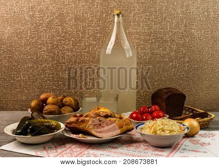 Ukrainian National Drink And Snack. The Big Bottle And Glass Of Moonshine On The Old Wooden Table