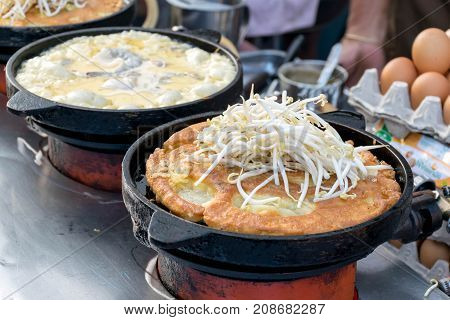 Cooking Oyster omelette in black metal pan