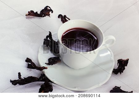 white porcelain mug with tea karkade on white tulle