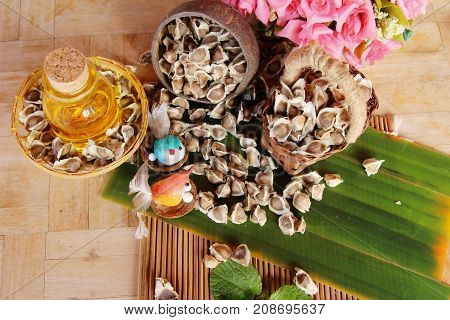 Moringa oleifera oil and seeds on wood background