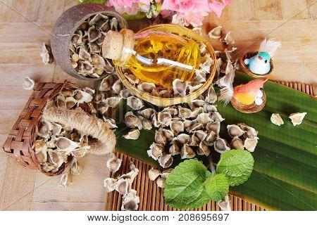 Moringa oleifera oil and seeds on wood background