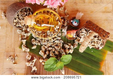 Moringa oleifera oil and seeds on wood background