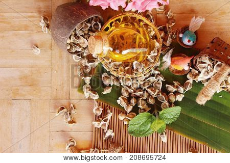 Moringa oleifera oil and seeds on wood background