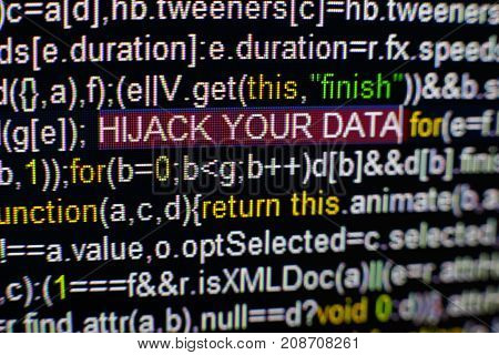 Macro photo of computer screen with program source code and highlighted HIJACK YOUR DATA inscription in the middle. Computer script on the screen with virus in it. Cyber security concept.