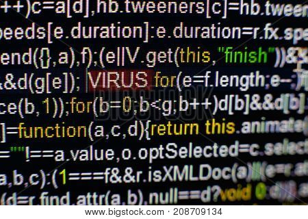 Macro photo of computer screen with program source code and highlighted VIRUS inscription in the middle. Computer script on the screen with virus in it. Cyber security concept.