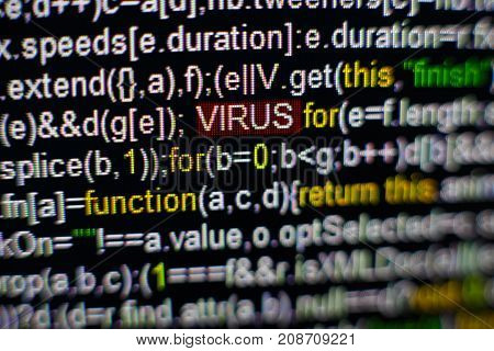 Macro photo of computer screen with program source code and highlighted VIRUS inscription in the middle. Computer script on the screen with virus in it. Cyber security concept.