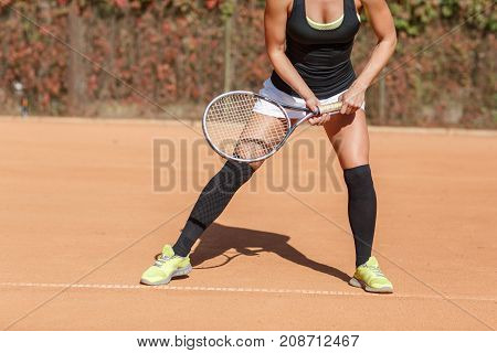 Legs of a young girl athlete near a tennis racket. Close-up. The concept of sport.