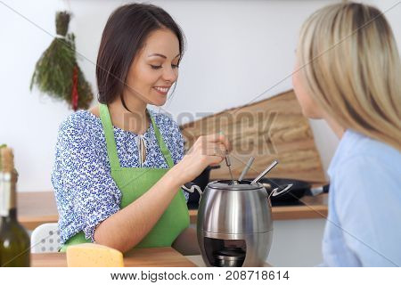 Two young happy woman making cooking in the kitchen. Friendship and culinary concept.