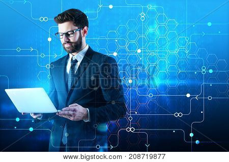 Handsome young businessman using laptop on abstract blue background with circuit and binary code. Communication concept. Double exposure