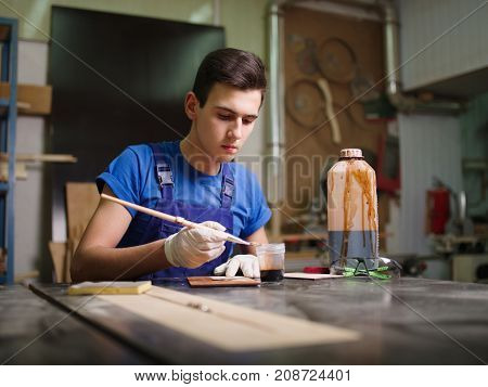 A wooden plate, on which the imprint of the paw imprinted patterns and inscriptions, the master began to apply the varnish close-up