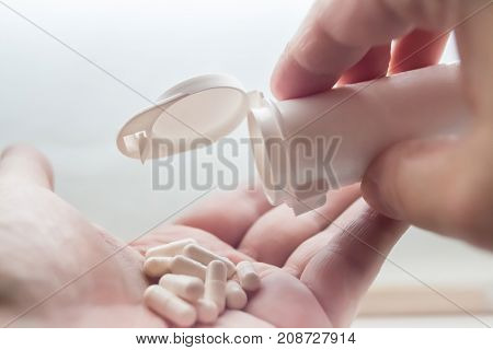 White Pills spill out of container on hand