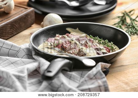 Frying pan with steak Diane on table