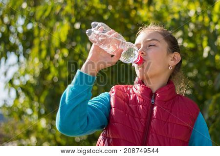 Beautiful girl drinking water after jogging in outdoor. A  beautiful girl is drinking water the hot sun in the park. Healthily concept. Healthy lifestyle concept. copy space. Portrait  beautiful girl
