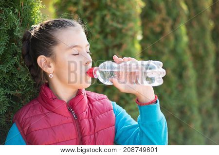 Beautiful girl drinking water after jogging in outdoor. A  beautiful girl is drinking water the hot sun in the park. Healthily concept. Healthy lifestyle concept. copy space. Portrait  beautiful girl